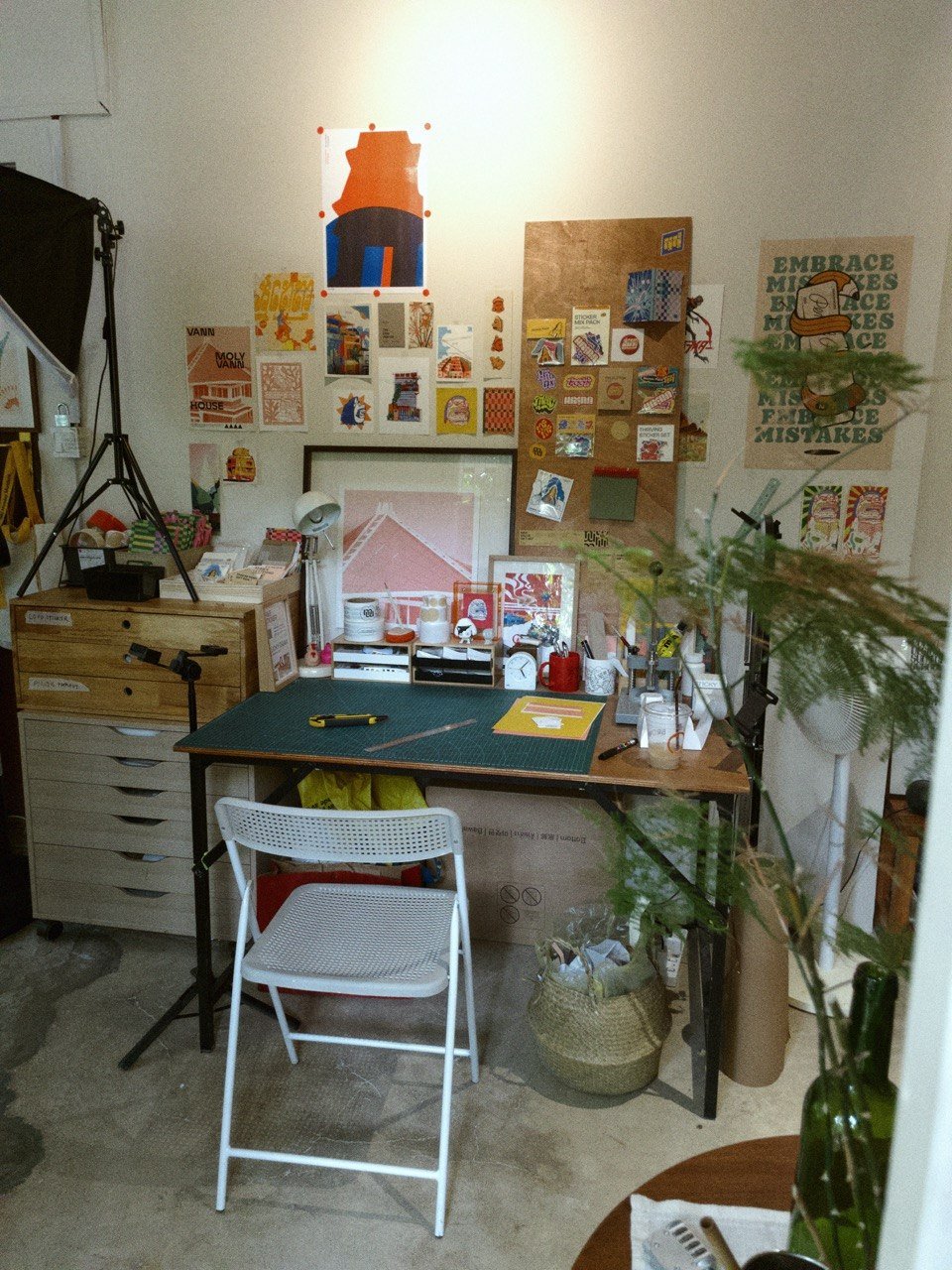 Monnyreak Ket studio with cutting mat, pinned sketches, and Embrace Mistakes poster